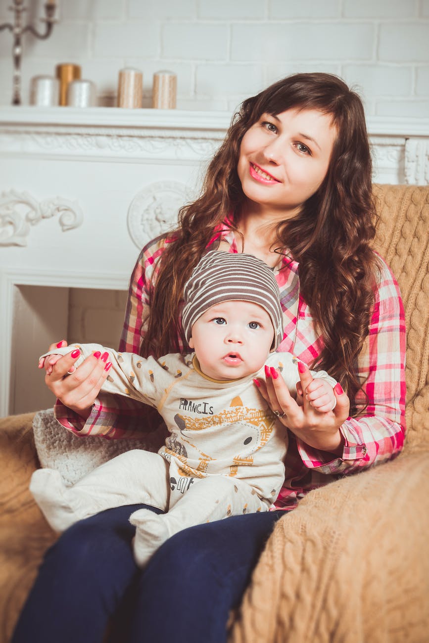 woman wearing red and white plaid shirt sitting on chair holding baby - Tips for Finding Perfect Babysitter