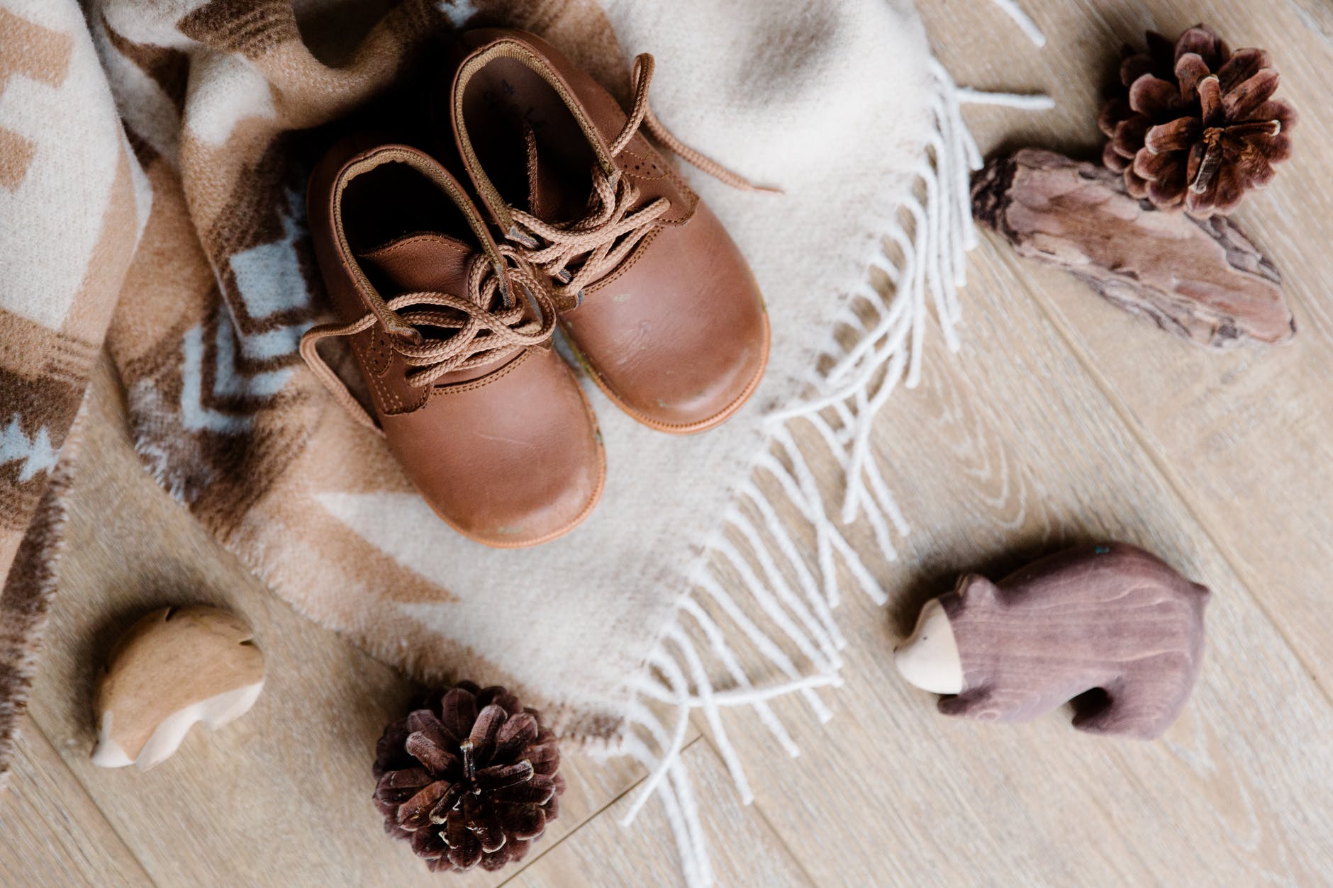 vintage children shoes on cozy plaid near decor elements on parquet